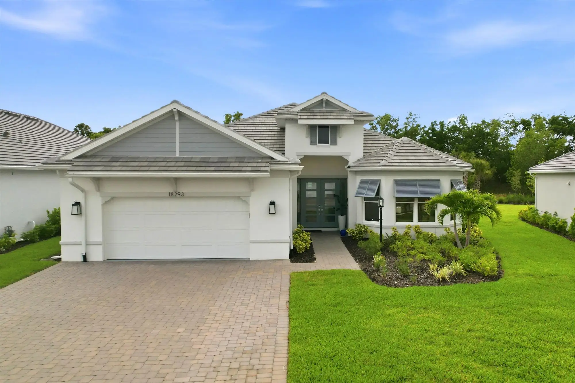 Front of a single-story Taylor Morrison home with a two-car garage, paver driveway and palm landscaping